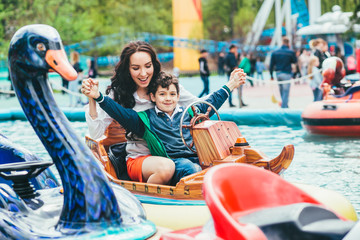 Een gelukkige moeder en zoon rijden samen op een draaimolen, glimlachen en hebben plezier op een kermis of pretpark.