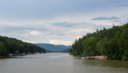 A beautiful summer landscape with a lake in the background of the mountains. People sail on a boat on the lake. Lake Lure, NC, USA