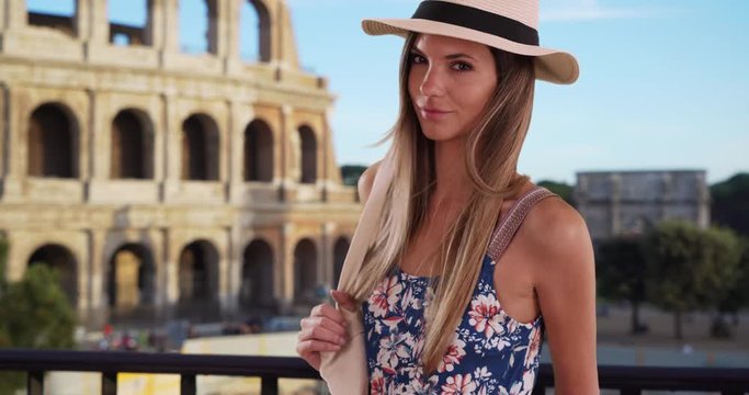 Portrait of attractive woman in summer outfit posing by Roman Colosseum, Stylish attractive woman in her 20s wearing fedora and romper standing outside in Rome, Italy, 4k