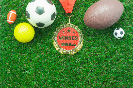Table top view aerial image of soccer or football season background.Flat lay accessories variety ball with gold medal on the artificial green grass wallpaper.Free space for design text and content.