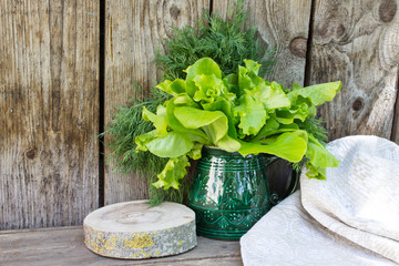 Bunch of dill and lettuce on a background of old boards. Copy space. Country style.