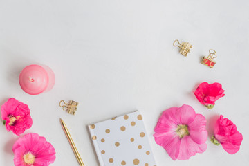 Flat lay desk with pink flowers, notebook and accessories