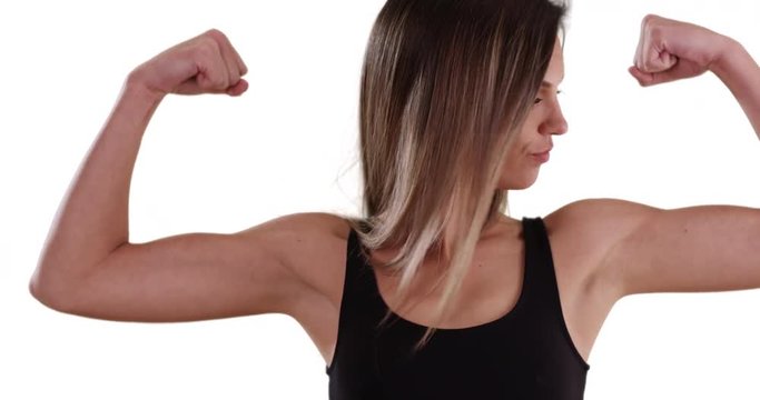 Athletic young woman flexing and kissing biceps on solid white background, Fit Caucasian girl in her 20s showing off arm muscles on solid white copy space, 4k