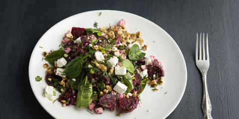 Beetroot salad with cottage cheese, baby spinach and walnuts. European cuisine. Organic food. Vegetarian appetizer. Healthy lifestyle. Simple side dish. Close up. Wide photo.
