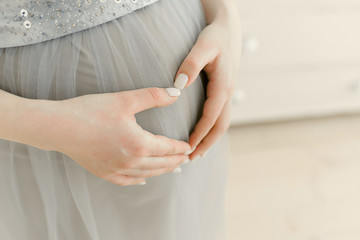 belly of a pregnant girl close-up. Gentle embrace and stroking