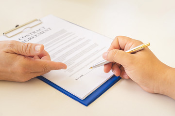 Businessman hands are pointing at the line needs autograph and signing contract.