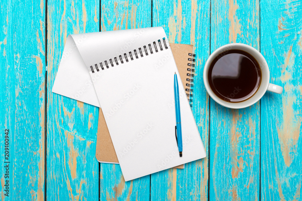 Wall mural Cup of coffee with notebook on wooden desk