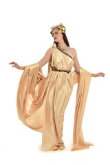 Obraz na płótnie Canvas full length portrait of brunette woman wearing long golden grecian gown, standing pose. isolated on white studio background.