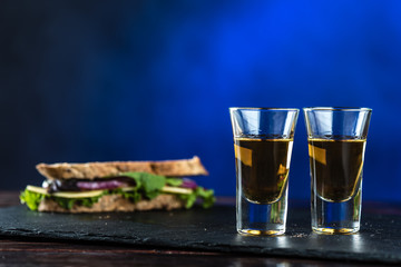 Two shots of tequila and a sandwich on slate