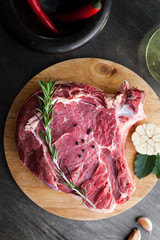 Raw beef fillet steak with herbs and spices on black wooden background