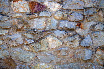 The wall is made of natural stone. Stone wall masonry is a natural material