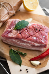 Raw pork bacon with spices and herbs on wooden background