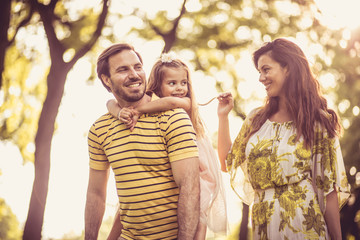 Happy family with little girl walking trough nature.