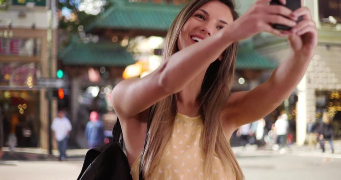 Happy millennial girl taking selfie with smartphone while in San Francisco city street, Woman in her 20s taking photo of herself with phone in San Francisco Chinatown, 4k
