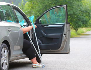 Disabled woman upgoing from a car. Transportation and travel for handicapped people.