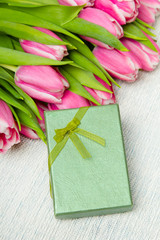 Pink tulip bouquet and small gift on light background,