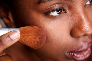 Close up beautiful woman applying makeup with brush for smooth matte finish