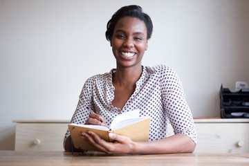 smiling black woman at home writing in journal