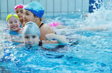 Happy children kids group at swimming pool class learning to swim