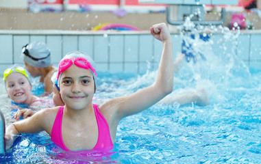 Happy children kids group at swimming pool class learning to swim