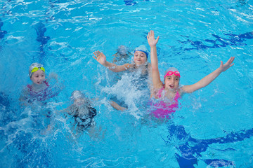 Obraz na płótnie Canvas Happy children kids group at swimming pool class learning to swim