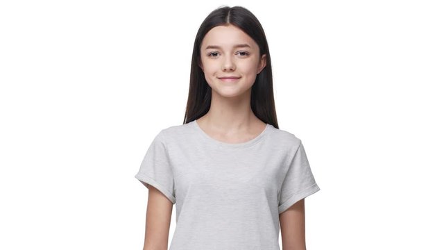 Portrait of lop-eared caucasian woman with long dark hair in basic t-shirt looking at camera with beautiful smile, isolated over white background in studio. Concept of emotions
