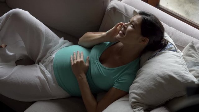 Pregnant Asian-american woman relaxing on a couch