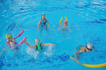 Happy children kids group at swimming pool class learning to swim