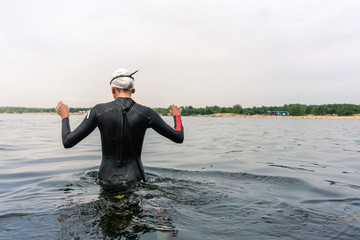 Woan in a wetsuit goes into the water to swim