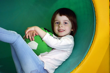 Girl with a soft ball at a green slide