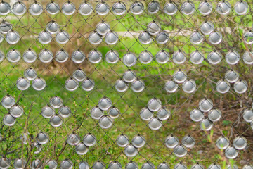 Metal chain-link fence decorated metal circles on a green grass background