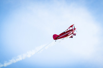 Fototapeta na wymiar Red airplane with propellers and white smoke