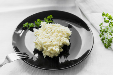 Cabbage salad with a sprig of parsley on a black plate on a white table