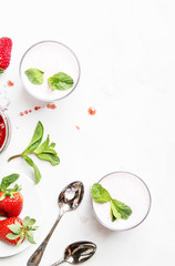 Strawberry dairy smoothies with berry and green mint, white background, top view