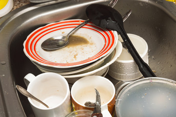Dirty unwashed kitchen utensils and dishes in the sink