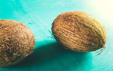 Two coconuts with shell on a blue colored background