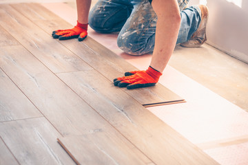Working with hands installs a laminate board, professional flooring installation