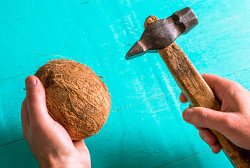 Coconut and an old hammer in the hands. Cracking coconut