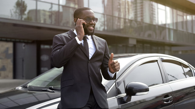 African American showing thumbs-up speaking on phone, manager concluded bargain