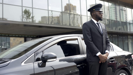 Driver of vip hotel service waiting for passengers near his car, ready to go