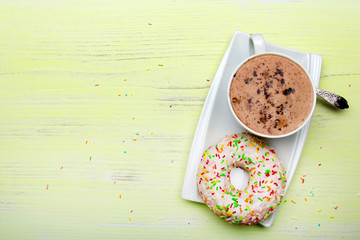 Cup of coffee and tasty donuts with icing and chocolate on green wooden background, copy space