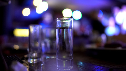 Shot of vodka standing on bar counter, night party, leisure, alcoholism issues