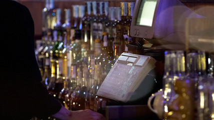 Restaurant worker typing on cash register, accepting order from customer