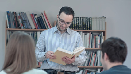 Portrait of young teacher reading book in the classroom