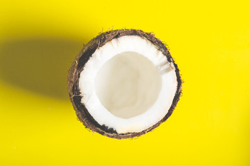 Half of coconut on a yellow minimalistic background