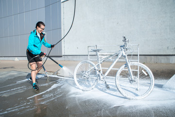 young sport woman washing bicycle at self-service car wash