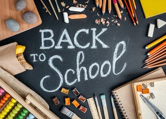 Variety of school supplies and white chalk lettering on black background. Top view. - 209115956