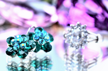 Close-up of green flower shaped earrings with geeen diamonds jewelery - reflection effect - silver ring in backgrounds