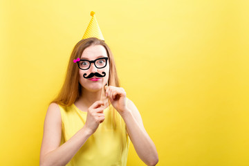 Young woman holding paper party sticks on a solid background