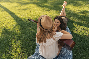 Fototapeta premium Beautiful women having fun playing guitar in the park.